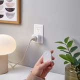 Person holding remote controlling lamp plug.