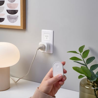Person holding remote controlling lamp plug.