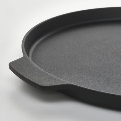 Black cast-iron pizza pan with handles. Round, flat surface.