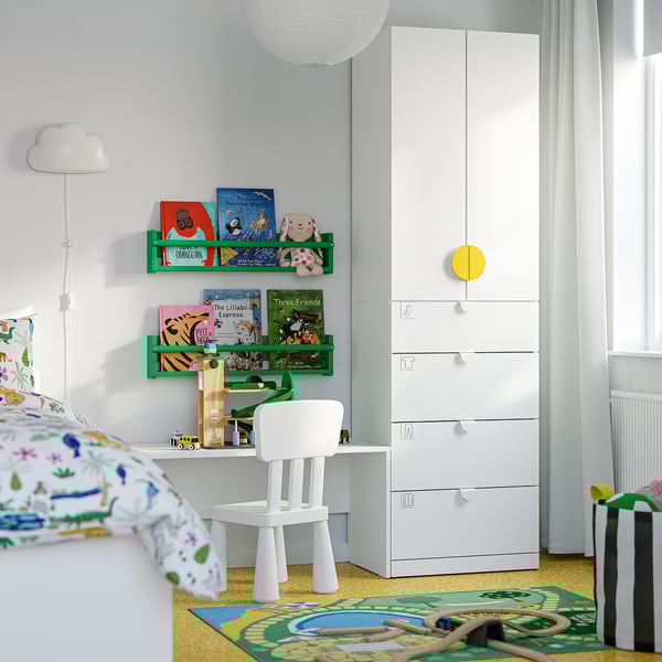 Kids room with white wardrobe, yellow carpet, green bookshelf, small desk & chair.