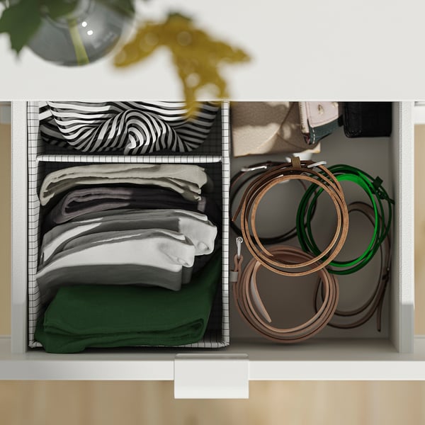 White drawer organiser with folded scarves in black, white, and green patterns. Right side holds brown and green belts.