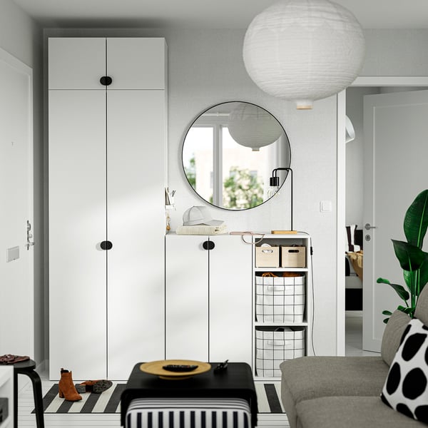 Modern entryway with white LASTARE cabinets, round mirror, hanging light, striped bench, and small shoe rack beneath tall wardrobe.