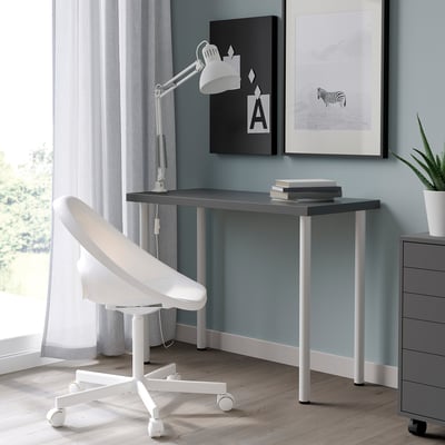 Modern minimalist workspace with white LINNMON table, matching chair, and wooden floor. Grey walls, light curtains, and large windows.