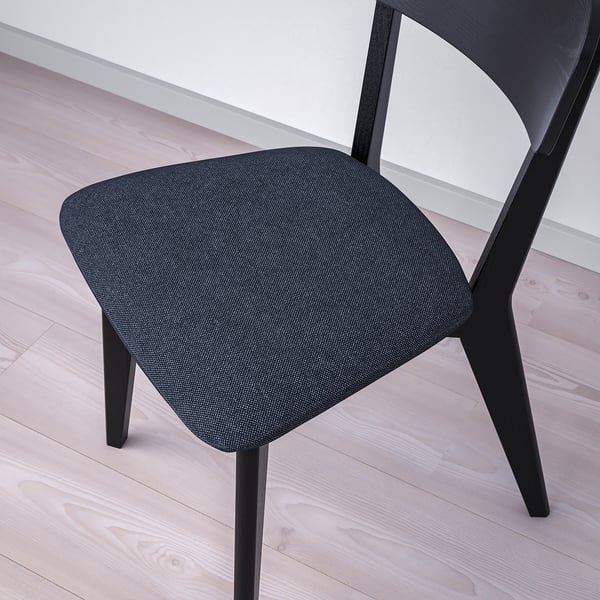 Modern black chair with cushioned seat on wooden floor. Stainless legs & comfortable design.