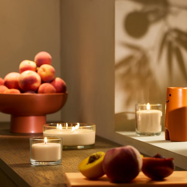 Cosy table setup with peaches, candles, and a fruit board.