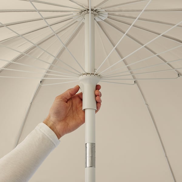 Hand holding adjustable parasol handle, tilting shade for comfort.