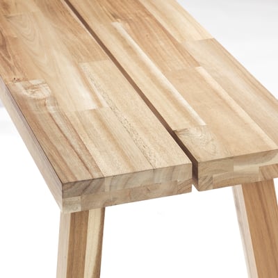 Wooden table edge detail. Solid acacia with smooth, light finish. Visible grain and minor variations. Simple, supportive legs.
