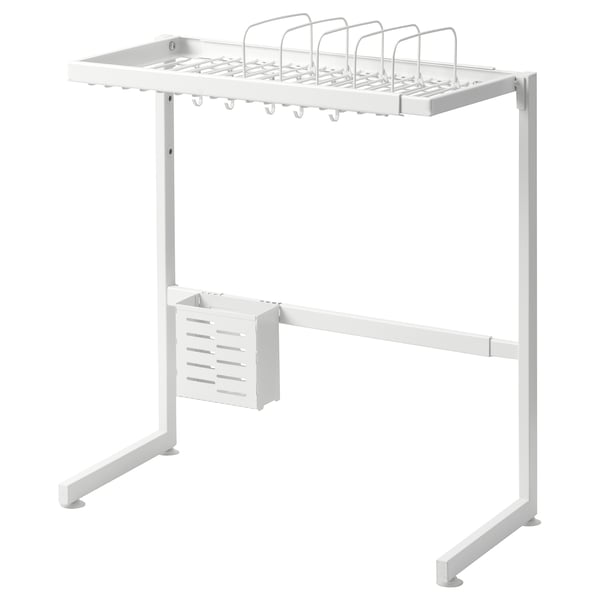 A white SKYGGFISK dish rack standing over a sink. Its made of metal with plastic feet, holding dishes, utensils, and cutlery.