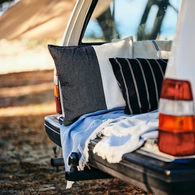 Truck bed with black, grey, striped pillows & blue blanket, showing size and design.