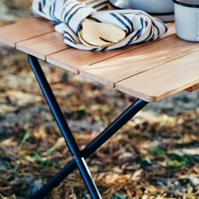 Foldable wooden table, light brown, black metal legs, rectangular, portable.