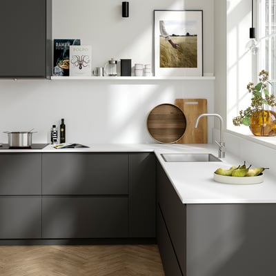 Modern kitchen with grey TÄRNHULT glass walls, white counter, steel sink, decor, and hanging light.