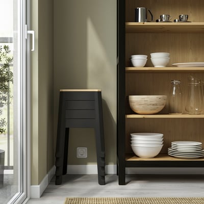 Modern kitchen with open shelves displaying white dishes. Dark wood stool with metal legs stands near green wall.