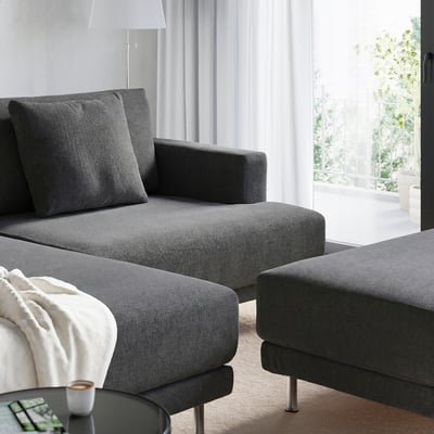 Grey modular sofa with large cushions & metal legs near windows with sheer curtains.