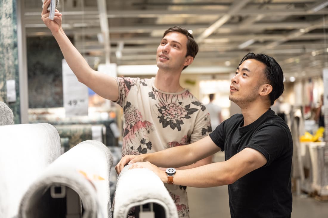 Two men look at rugs in an IKEA store.