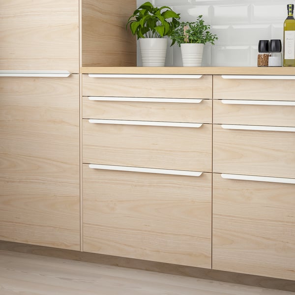 Modern light brown kitchen cabinets with silver handles, sleek design, houseplants on countertop. Easy to clean.