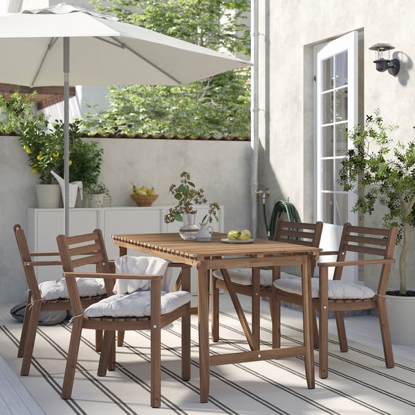 Small outdoor dining set with 4 brown wooden chairs and table. Cushions are white.