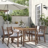 Small outdoor dining set with 4 brown wooden chairs and table. Cushions are white.