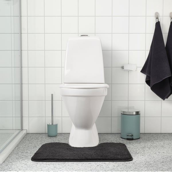 White toilet on black mat, aquabrush and bin. Mat: BACKMÅRA, dark grey, 100% polyester, thick, soft.