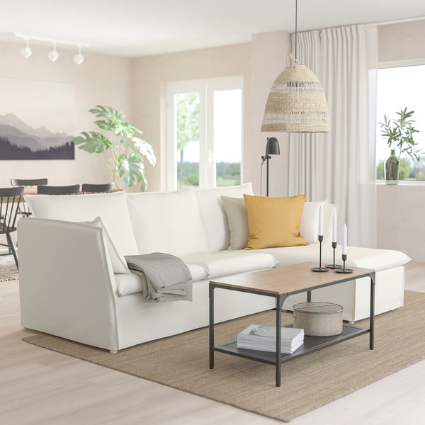 White BACKSÄLEN sofa with chaise, yellow/gray pillows, wooden coffee table, modern lamp, large window.