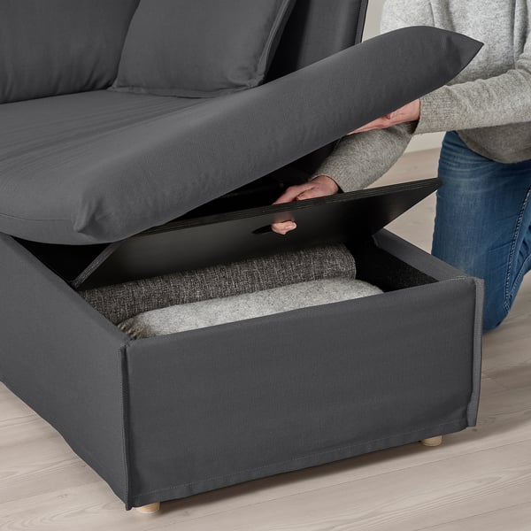 Person lifting gray sofa section revealing storage compartment.