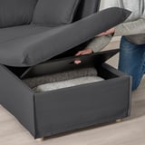 Person lifting gray sofa section revealing storage compartment.
