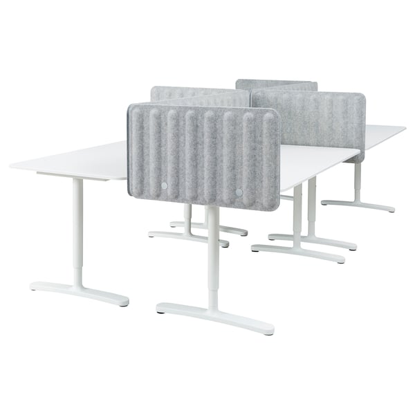 Four white workstations with adjustable desks and grey privacy screens.