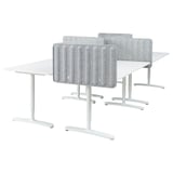 Four white workstations with adjustable desks and grey privacy screens.
