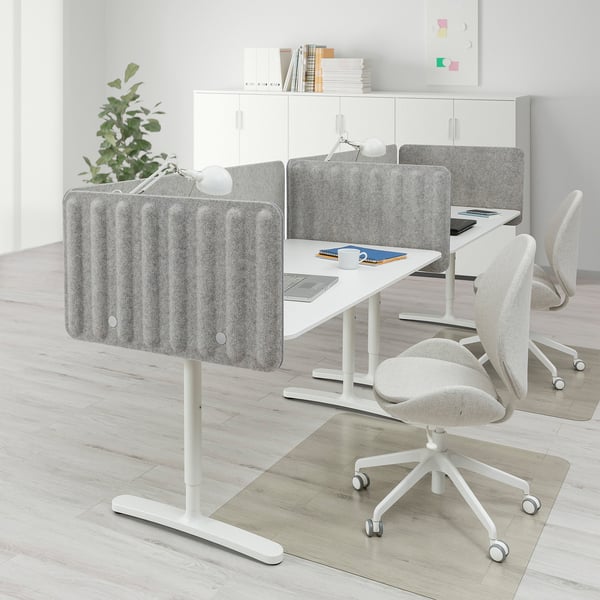 Modern office with BEKANT desks, screens, & large cabinet. Spacious, adjustable heights.