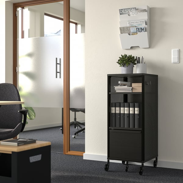 Black BEKANT office unit with shelves, drawer, plant, and desk.