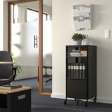 Black BEKANT office unit with shelves, drawer, plant, and desk.