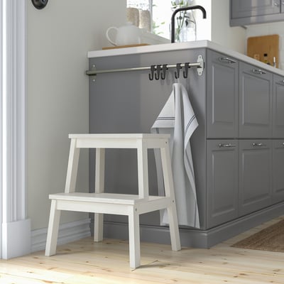 White BEKVÄM stool beside gray cabinets. Compact, stable aspen wood, moves easily.