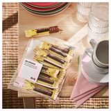 IKEA BELÖNING chocolate bars, packaged and partially unwrapped, near plates and cups.