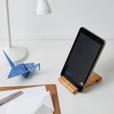 Tablet stand holds device upright next to desk lamp and paper crane on a desk.