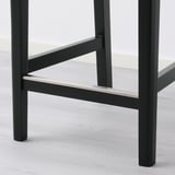 Modern bar stool with sleek, black metal legs and support brackets, featuring a sturdy design for comfort and stability.