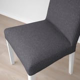 Grey upholstered chair with white legs on wooden floor. Modern, boxy design with high back.
