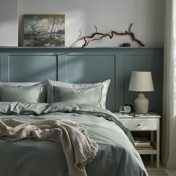 Bedroom with BERGPALM grey striped duvet, nightstand, lamp, and decor.