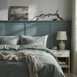 Bedroom with BERGPALM grey striped duvet, nightstand, lamp, and decor.