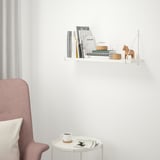 White BERGSHULT shelf with books, decor, and chair.