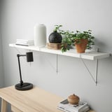 Minimalist wall shelf with books, lamp, vase, and plant.