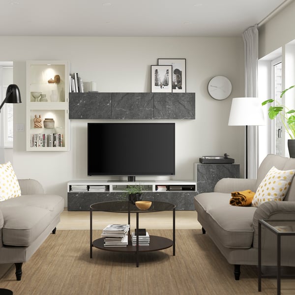 Modern living room with BERGSVIKEN tv stand, flat screen tv, gray sofas, colorful pillows, glass coffee table, and tall lamp.