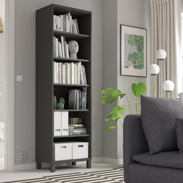 Black BESTÅ bookcase with books & decor, between sofa & wall with poster.