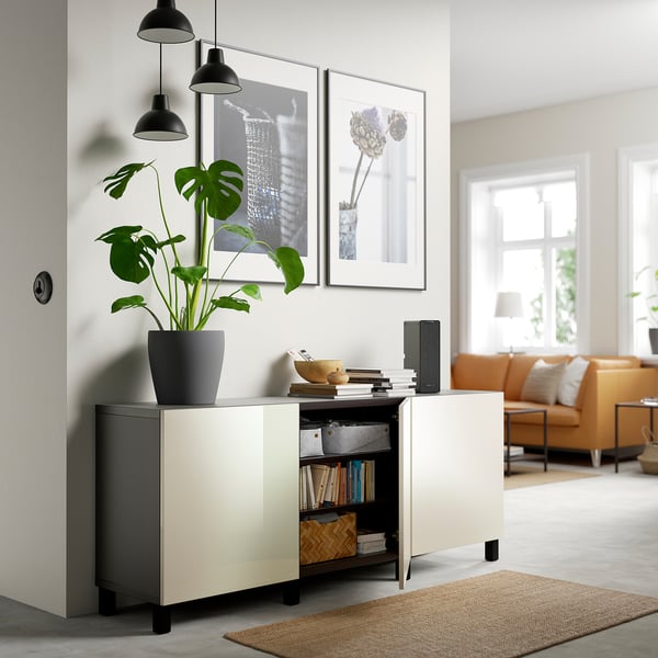 Modern living room with BESTÅ sideboard, books, plant, and soft-close door. Decor includes art and pendant lamps.
