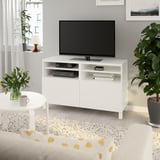 White BESTÅ tv stand with flat-screen tv, adjustable shelves, electronics, vase, plant, wall picture.