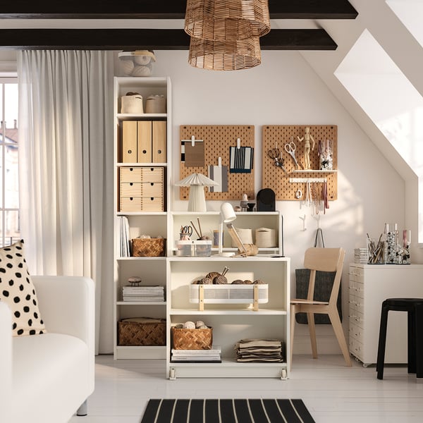 Home office with BILLY bookcase, table, and open storage. Pegboard with tools, cozy chair, rug, and large window with pendant light.