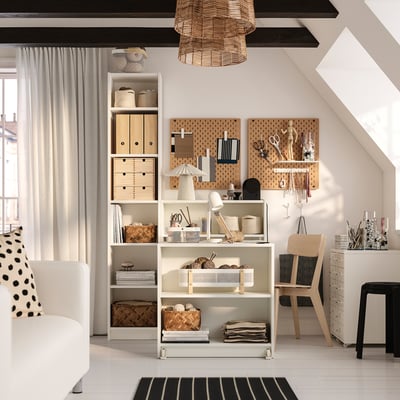 Home office with BILLY bookcase, table, and open storage. Pegboard with tools, cozy chair, rug, and large window with pendant light.