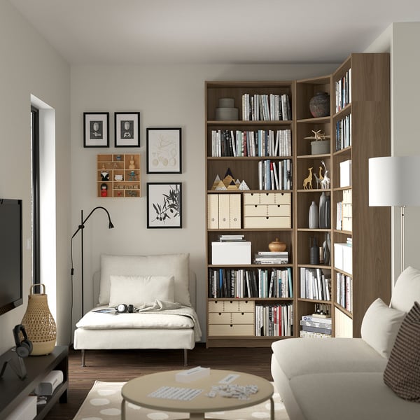 Cozy living room with BILLY bookcase, chair, couch, coffee table, and lamp. Artwork and decor on walls.