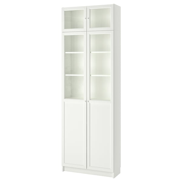 A tall, white BILLY bookcase with glass doors. It has multiple adjustable shelves for versatile storage.