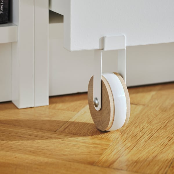 White BILLY bookcase with wooden floor, featuring a circular drawer with castors.
