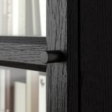 Close-up of a black wooden door handle with textured surface attached to a smooth, dark wooden door.