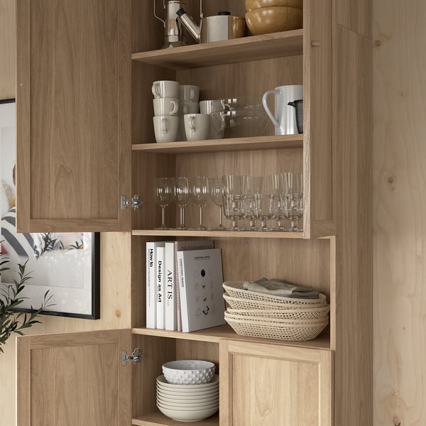 Wooden bookcase with glassware, mugs, books, and bowls neatly organized on shelves.